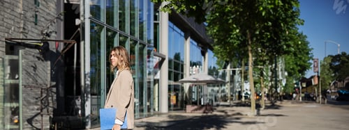 Preview: Portrait of businesswoman in beige suit and high heels walking on street. Corporate woman going to