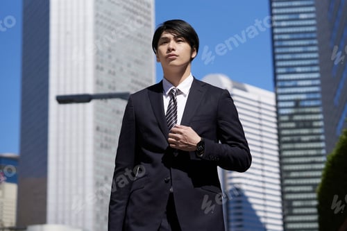Preview: A Japanese male businessman walks through an office district.