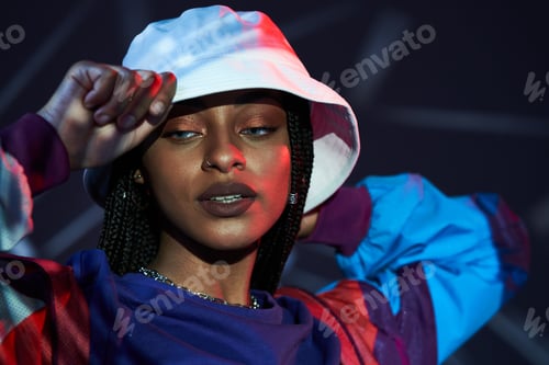 Preview: Portrait of stylish young ethnic lady looking away in illuminated studio