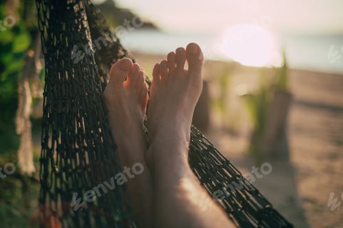 Preview: A Man Is Resting In A Hammock. Close-Up Of Legs. Sunset Light. Tropical Island