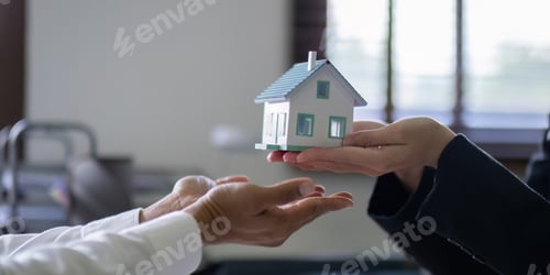 Preview: Hands Exchanging House Model in Real Estate Negotiation