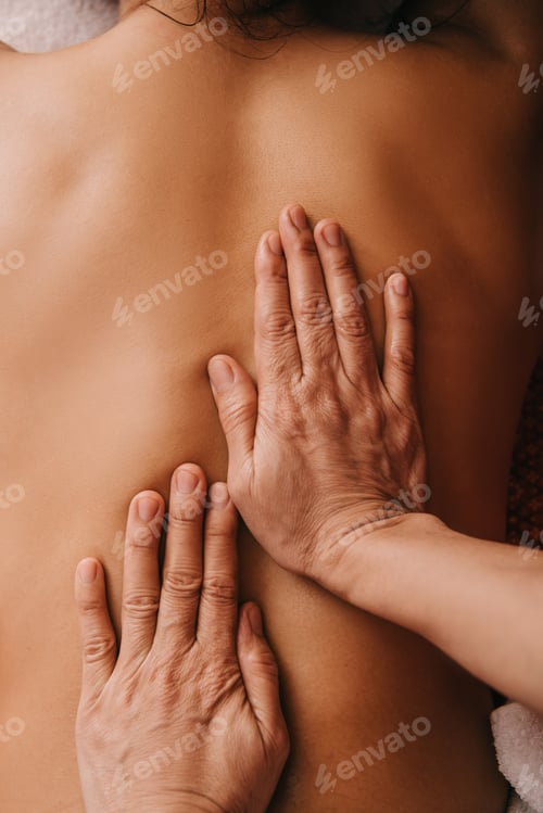 Preview: cropped view of masseur doing back massage to woman in spa