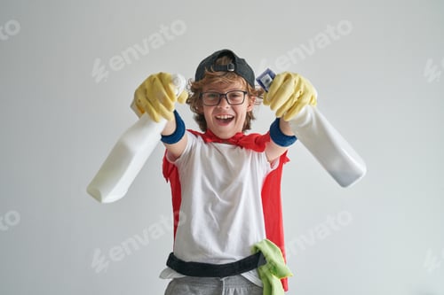 Preview: Joyful boy in housekeeper costume standing with detergent bottle