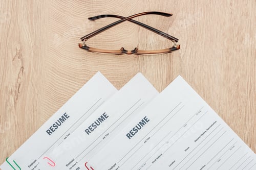 Preview: top view of resume templates and glasses on wooden surface