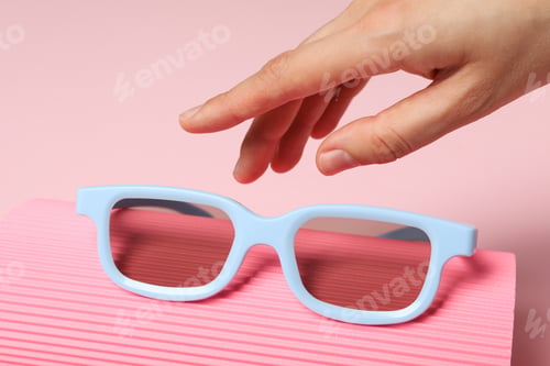 Preview: Sunglasses in hand on purple background, close up
