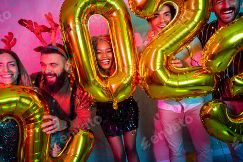 Preview: Friends having fun at New Year party, holding giant balloons 2023