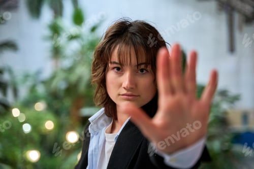 Preview: Young businesswoman making stop sign with hand in office