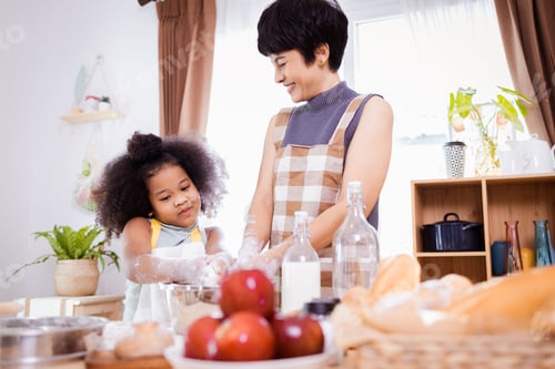 Preview: Happy African American mother and daughter having fun while preparing cookie dough at home