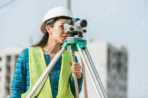 Preview: Surveyor in hardhat and high visibility jacket looking in digital level