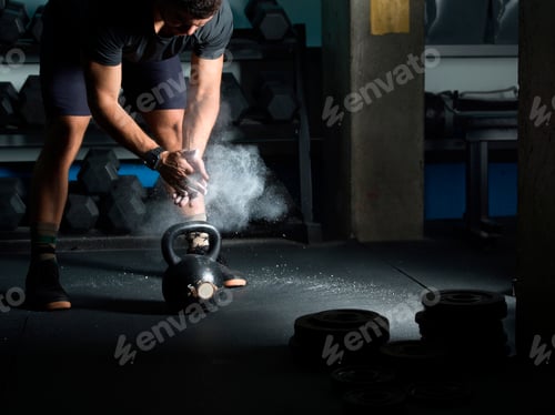 Preview: Man powdering hands before lifting kettlebell in gym