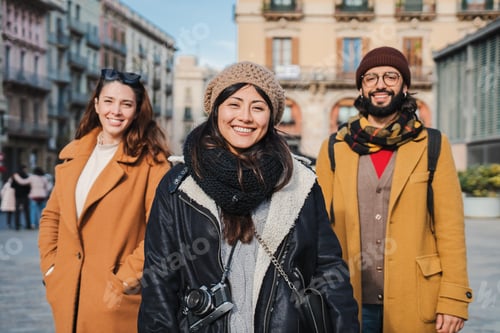 Preview: Group of tourist friends standing at european city street smiling and looking at camera. Portrait of
