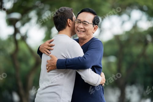 Preview: Father and son hugging in park
