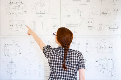 Preview: Young woman engineer shows something on the drawings
