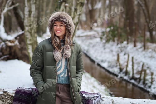 Preview: Photo a young woman wearing a cozy winter hat and winter coat on forest path.Millennial life.
