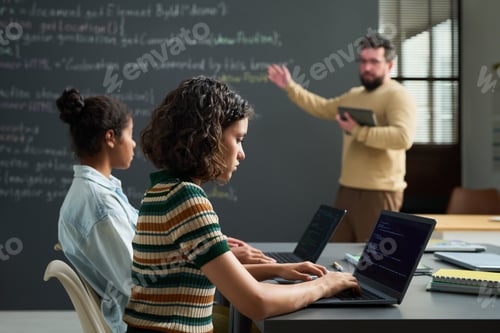 Preview: Teenage Girls Coding on Laptops While Male Teacher Explaining Programming Concepts