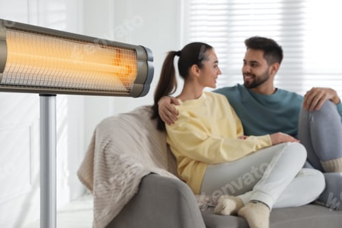 Preview: Electric heater and young couple on sofa indoors