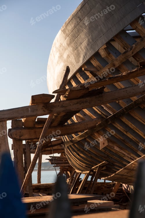 Preview: Sunset hues cast upon an ancient wooden ship under construction