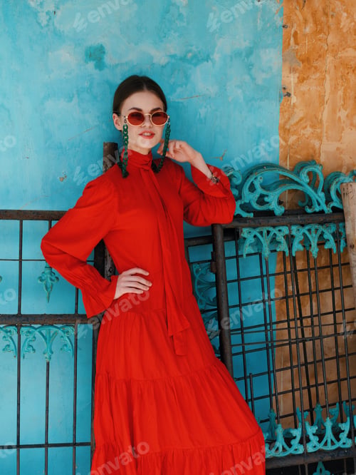 Preview: Elegant woman in red dress striking a pose against vibrant blue and yellow backdrop