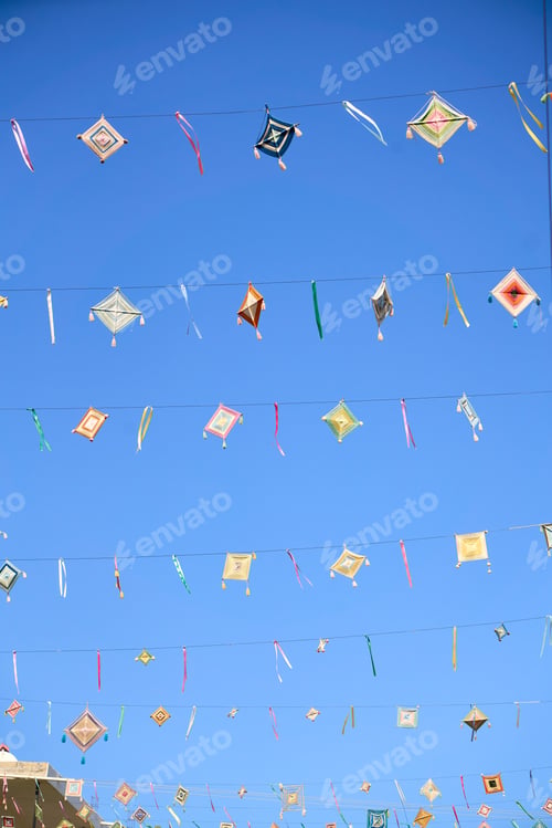 Preview: God's eyes or Ojos de Dios hanging over a street against a bright blue sky