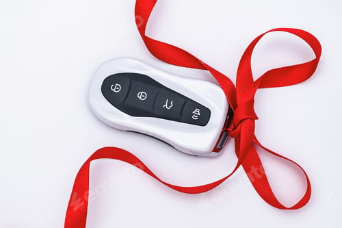Preview: Concept and gift idea. Flat lay smart car key with a red gift ribbon on a white background. Electron