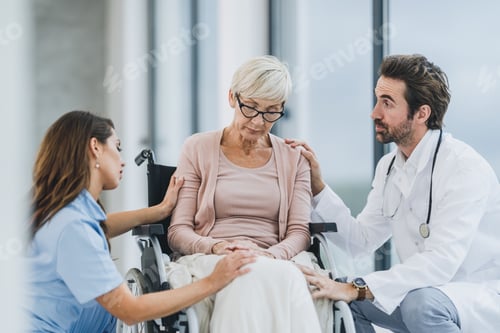 Preview: Doctor And Nurse Talking With Their Senior Female Wheelchair-Bound Patient At The Hospital