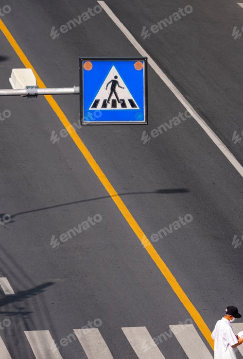Preview: Focus at overhead electric pedestrian crossing sign with elderly man is walking on zebra crosswalk