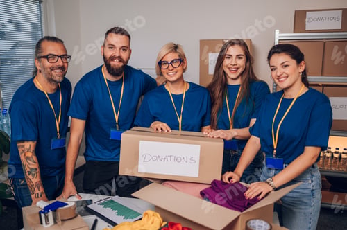 Preview: Diverse volunteers working in a charity donation center and packing clothes and food