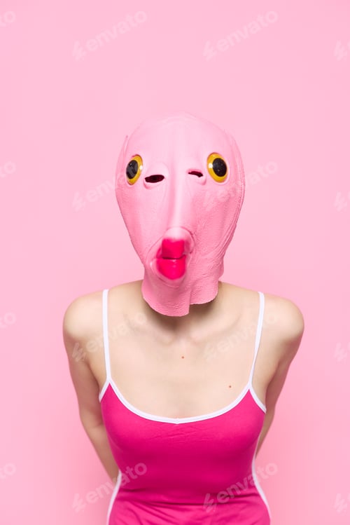 Preview: Crazy woman in pink fish head costume poses on pink studio background, provocative Halloween costume