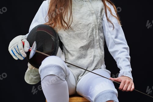 Preview: Portrait of woman dressed in fencing costume on black background