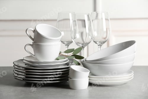 Preview: Set of clean dishes on table against blurred background