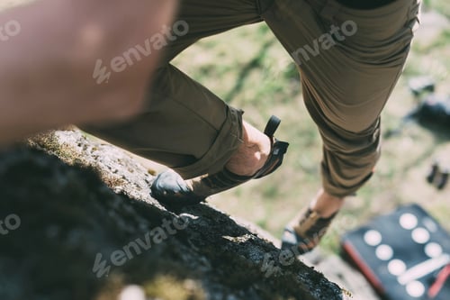 Preview: Waist down view of male boulderer climbing up boulder, Lombardy, Italy