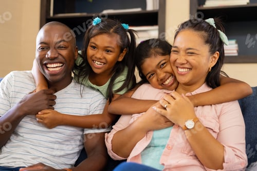 Preview: Happy Family Smiling and Embracing on Couch Indoors