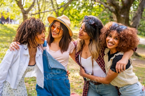Preview: Four young women embracing friendship in a sunny park