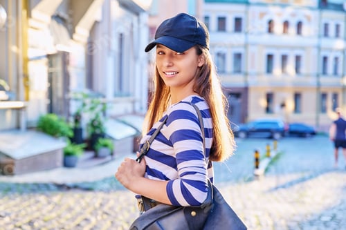 Preview: Outdoor portrait of teenage girl in black cap, city street background