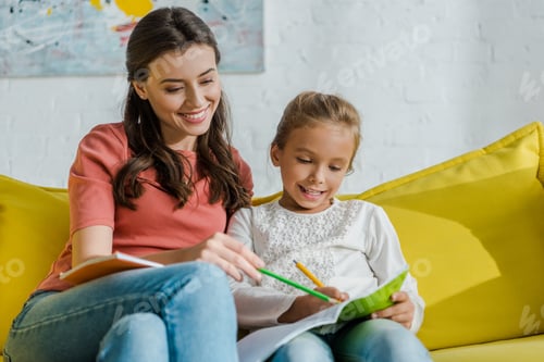 Preview: Woman and Girl Drawing Together on Yellow Couch