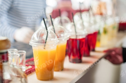 Preview: Various soft drinks in plastic cups with a straw on display at a street market.