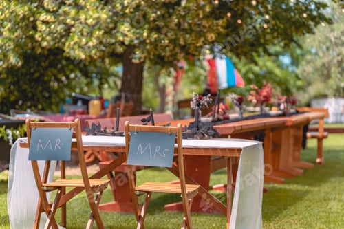 Preview: Outdoor wedding reception setup with Mr. and Mrs. signs on chairs
