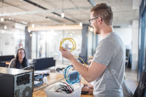 Preview: Man holding cables in office with colleague