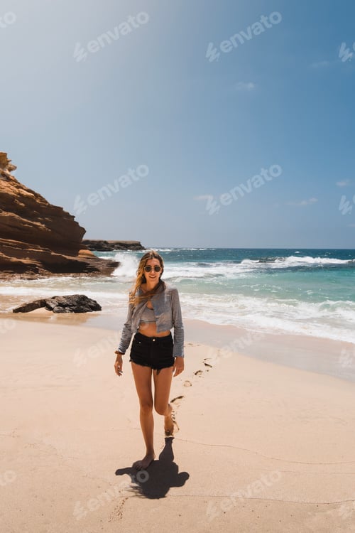 Preview: Happy and fit young Caucasian woman walking on the sand of Playa de los Ojos