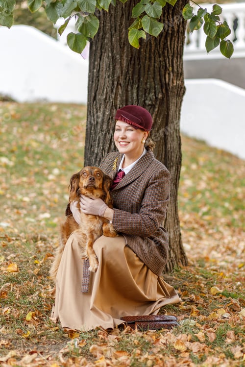 Preview: Brunette in vintage clothes and a hat with a dog in an autumn park. Retro style