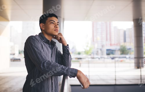 Preview: Millennial guy on balcony near office building