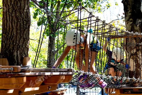 Preview: Cute children. Boy and girl climbing in a rope playground structure at adventure park.