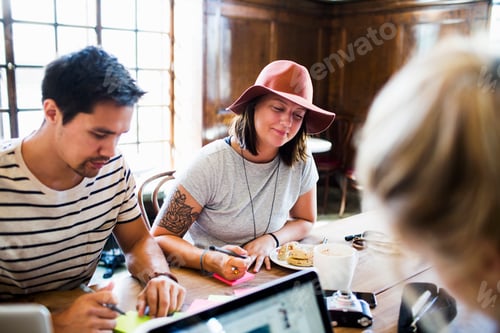 Preview: Friends doing freelance work at table in cafe