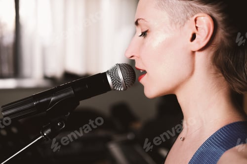 Preview: young female rock singer with microphone, singing. side view. close up. woman with short hair