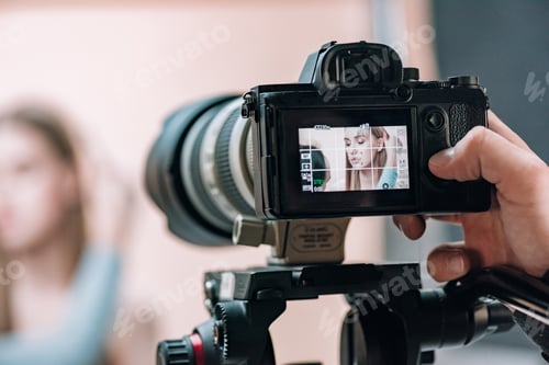 Preview: Selective focus of beautiful model on camera display in photo studio