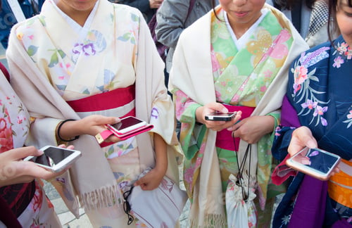 Preview: Women wearing traditional Japanese kimonos holding smartphones.