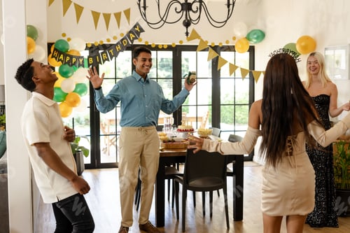 Preview: Friends celebrating birthday at home, dancing and laughing with joyful expressions