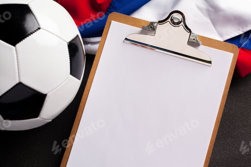 Preview: Soccer preparation with a clipboard and a ball on a dark surface