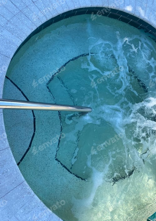 Preview: View from above of an outdoor hot tub with bubbling jets and a railing for safety on the steps