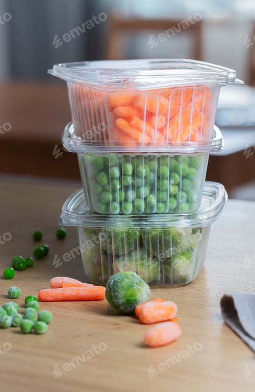 Preview: Frozen vegetables green peas in the storage box on the kitchen table, vertical orientation